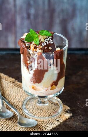 Dessert con gelato con pere in camicia e salsa al cioccolato guarnita con menta fresca Foto Stock