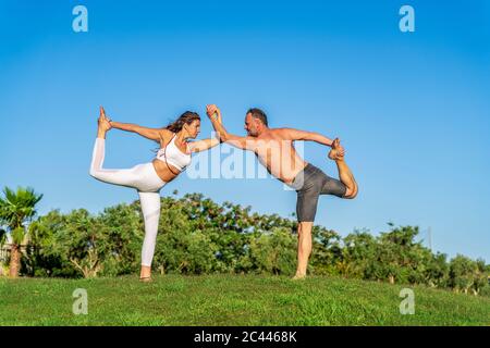 Coppia matura che fa yoga sul prato al sole insieme Foto Stock