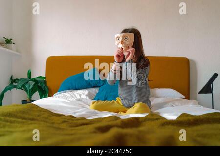 Ragazza che gioca con il cranio senza denti seduto a letto a casa Foto Stock