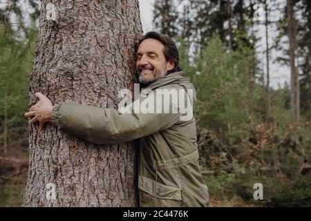 Tronco di albero hugging escursionista maturo Foto Stock
