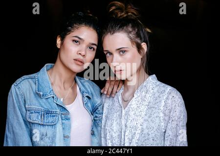 Ritratto di due giovani donne davanti a sfondo nero Foto Stock