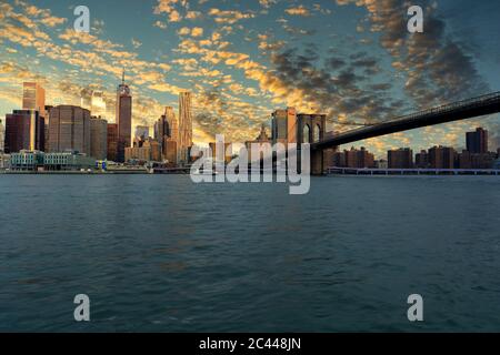 USA, New York, New York City, East River e Brooklyn Bridge all'alba con lo skyline di Manhattan sullo sfondo Foto Stock