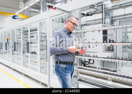 Uomo che utilizza lo scanner di codici a barre su un prodotto in fabbrica Foto Stock