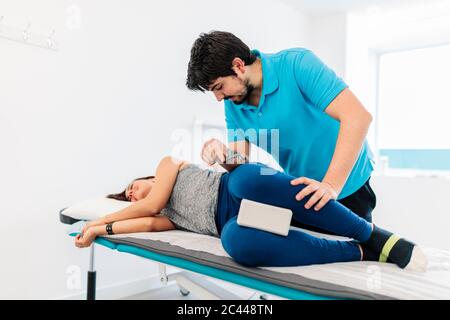 Terapeuta per non vedenti che tratta la gamba della donna in clinica Foto Stock