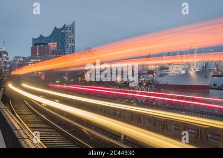 Germania, Amburgo, Train i sentieri leggeri lungo la linea ferroviaria sopraelevata al tramonto Foto Stock