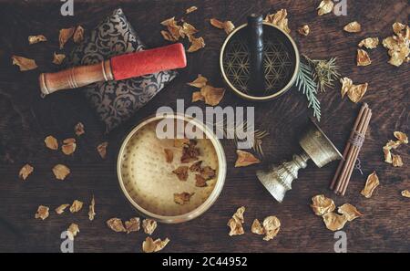 Piatto a tema tibetano con esempi di due diverse bocce cantanti - un marrone scuro, e uno di colore oro, e un antico portaincenso Foto Stock