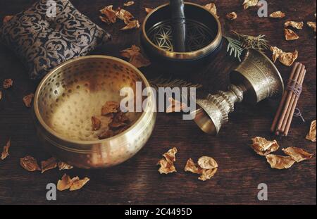 Primo piano a tema tibetano con esempi di due diverse ciotole cantanti: Marrone scuro, oro e portaincenso dall'aspetto antico Foto Stock