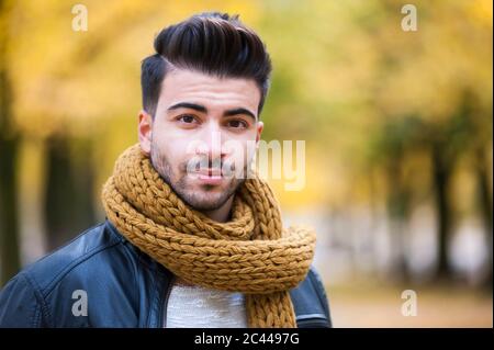 Bel giovane con sciarpa al parco durante l'autunno Foto Stock