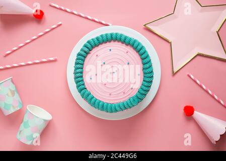 Studio shot di torta di compleanno, cannucce per bere, tazze monouso, cappelli da festa e decorazione a forma di stella Foto Stock