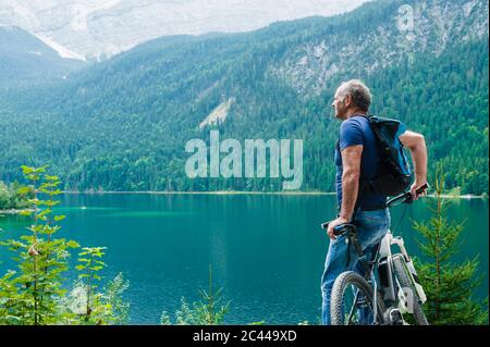 Uomo anziano con e-bike godendo la vista su Eibsee Foto Stock