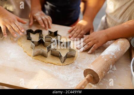 Vista ritagliata dei bambini che tagliano i biscotti a forma di stella Foto Stock