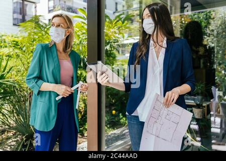 Due agenti immobiliari che indossano maschere di faccia mentre ispezione all'aperto area della casa Foto Stock