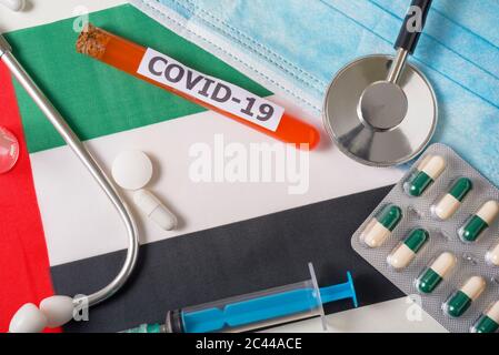 Coronavirus, il concetto COVid-19. Vista dall'alto maschera respiratoria protettiva, stetoscopio, siringa, pillole sulla bandiera degli Emirati Arabi Uniti. Un nuovo outb Foto Stock