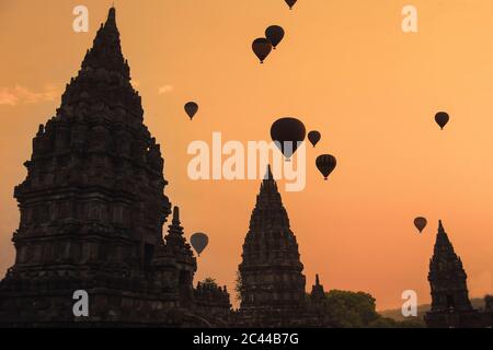 Indonesia, Regione Speciale di Yogyakarta, Silhouette di mongolfiere che sorvolano il tempio Prambanan al tramonto della moodia Foto Stock