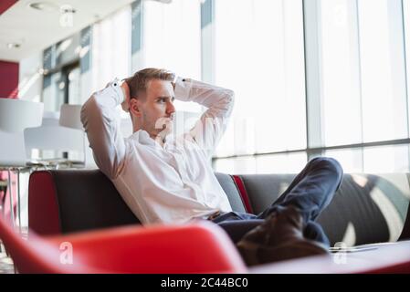 Uomo d'affari seduto sul divano moderno ufficio, pensando Foto Stock
