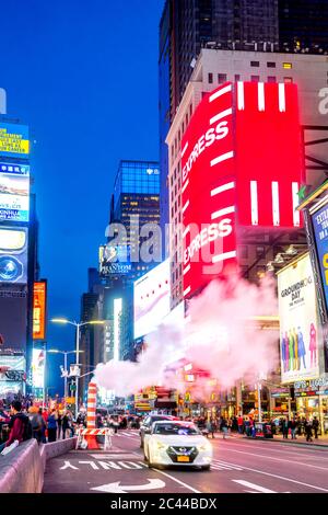 USA, New York, New York City, Smoke che galleggia sulle auto passando attraverso Times Square al tramonto Foto Stock