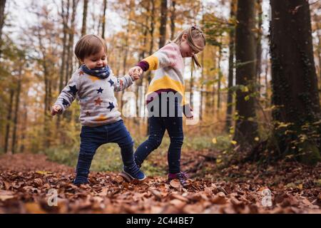 Germania, Baden-Wurttenberg, Lenningen, due bambini che giocano nella foresta d'autunno Foto Stock