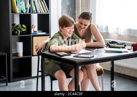 Madre che homeschooling suo figlio a casa Foto Stock