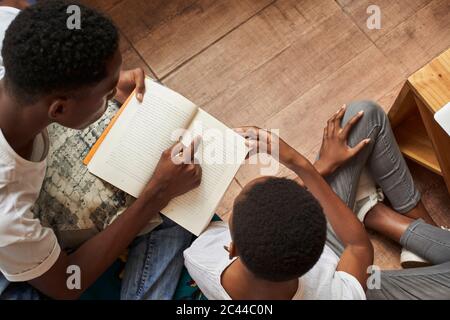 Vista dall'alto del libro di lettura di una giovane coppia a casa insieme Foto Stock