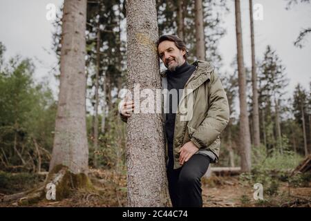 Tronco di albero hugging escursionista maturo Foto Stock