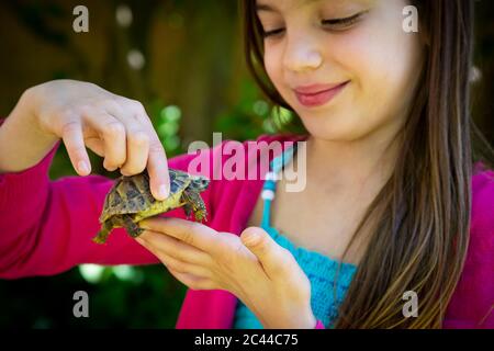 Sorridente le mani della ragazza che tiene piccola tartaruga Foto Stock