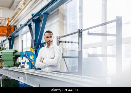 Uomo d'affari in piedi a metallo asta nel salone della fabbrica Foto Stock