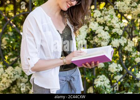 Donna sorridente la lettura di un libro Foto Stock