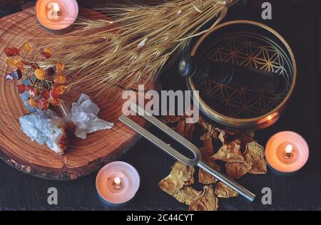 Altare Wiccan strega preparato per il mago di guarigione del suono con 741hz diapason fork e tibetano ciotola canto. Giacitura piana esoterica con piante secche, candele Foto Stock