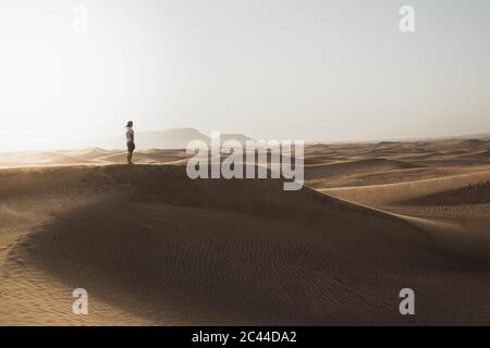 A metà distanza dal turista maschile che si trova sulle dune di sabbia nel deserto a Dubai, Emirati Arabi Uniti Foto Stock