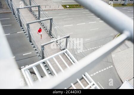 Giovane uomo che corre su un ponte sopra una strada Foto Stock