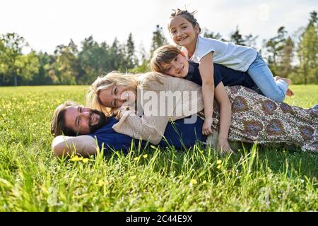 Famiglia felice che si distende sull'erba durante la giornata di sole Foto Stock