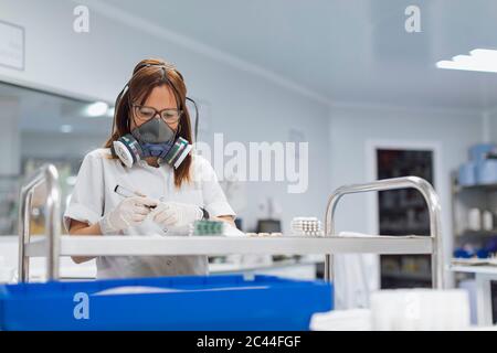 Una donna matura e sicura che tiene il marcatore mentre si guardano le pillole in laboratorio Foto Stock