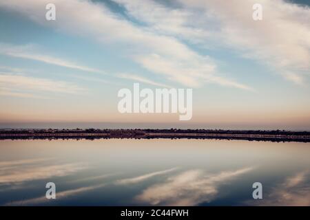 Vista panoramica del lago calmo contro il cielo nuvoloso durante il tramonto Foto Stock