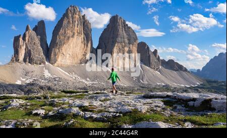 Ragazzo camminando sulla terra contro i pinnacoli a Tre Cime di Lavaredo, Italia Foto Stock