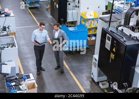 Due imprenditori con appunti parlando in fabbrica Foto Stock
