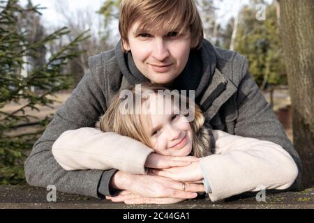 Ritratto di sorridente ragazza appoggiata sulle mani del padre in cortile durante il giorno di sole, Tarusa, Russia Foto Stock