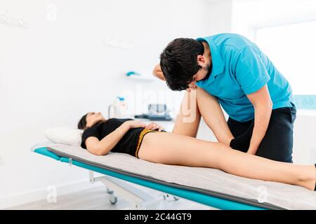 Terapeuta fisica per non vedenti che tratta la gamba della donna in clinica Foto Stock