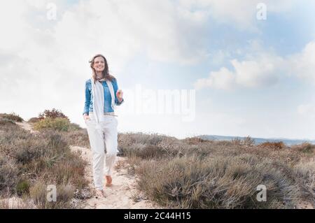 Donna felice passeggiando sulle dune di mare, Sardegna, Italia Foto Stock