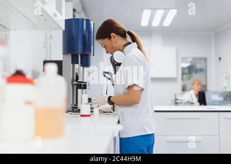 Medico femminile maturo che lavora mentre si sta alla scrivania in laboratorio Foto Stock