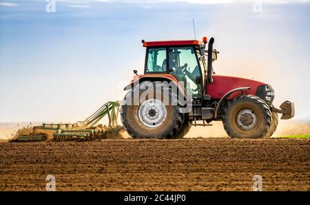 Coltivatore in campo di aratura trattore in primavera Foto Stock