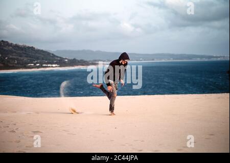 Giovane uomo che salta in spiaggia contro il cielo a Tarifa, Spagna Foto Stock