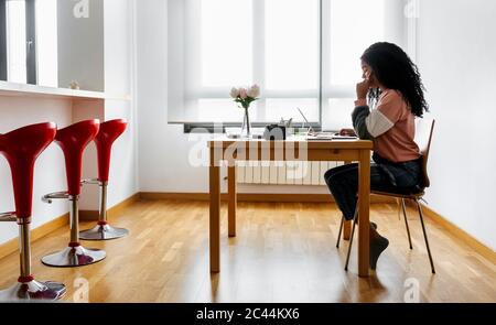 Giovane donna che lavora da casa utilizzando un computer portatile Foto Stock