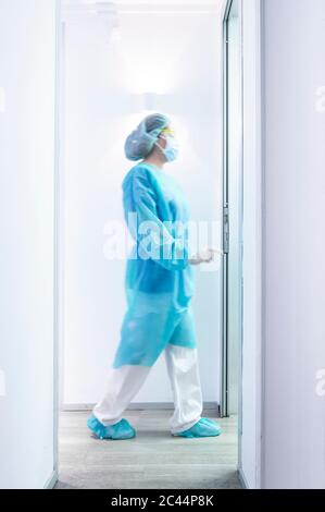 Dentista femminile maturo che cammina in un corridoio illuminato Foto Stock
