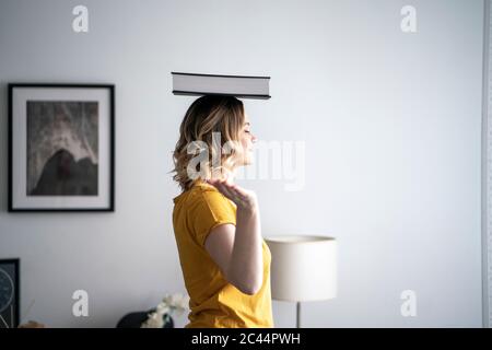 Donna a casa equilibrando un libro sulla sua testa Foto Stock