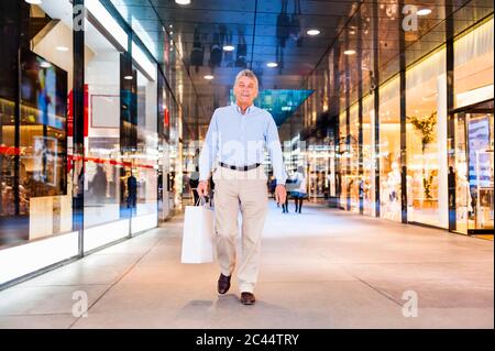 Ritratto di felice anziano con borsa in un centro commerciale Foto Stock