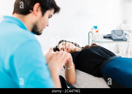 Terapeuta fisica per non vedenti che tratta la mano della donna in clinica Foto Stock