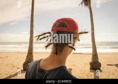 Costa Rica, provincia di Puntarenas, Puntarenas, Vista posteriore di un giovane uomo che indossa dreadlock guardando l'oceano da Playa Santa Teresa Foto Stock