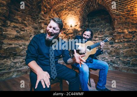 Uomo che suona flamenco alla chitarra mentre cantante canta in nightclub Foto Stock