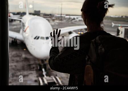 Sudafrica, Johannesburg, Vista posteriore di donna che guarda l'aereo su asfalto dal terminal dell'aeroporto Foto Stock