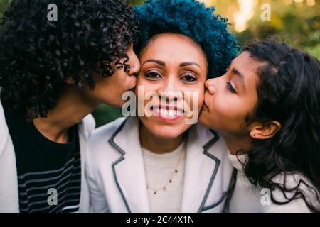 Primo piano di bambini amorevoli che baciano sulle guance della madre nel parco Foto Stock